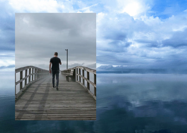 A cloudy sky reflected on water with a photo of a man walking down a foggy pier. Photos by Lindsay Windham