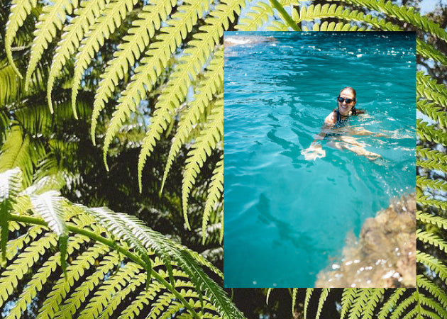 A photo of a woman swimming in bright blue water sits on top of a photo of bright green ferns