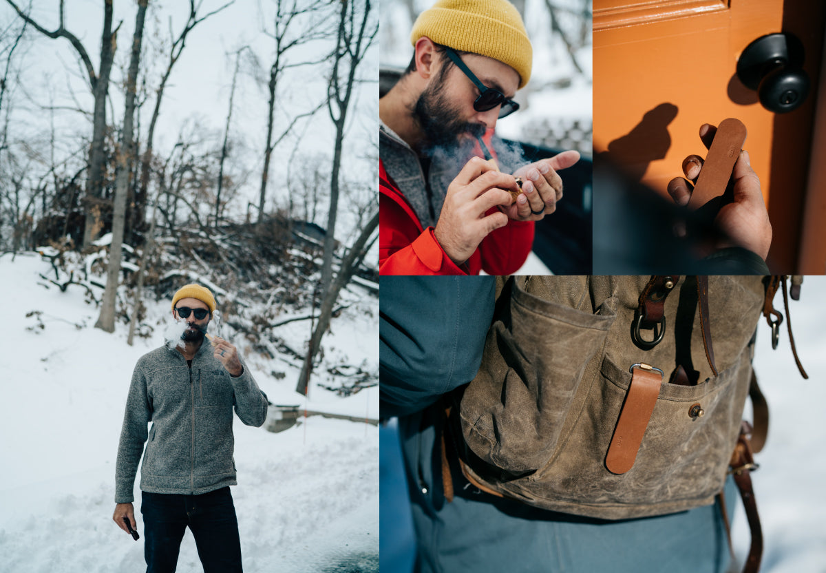 A man lights a pipe outside on a cold, snowy day with Distil Union gear
