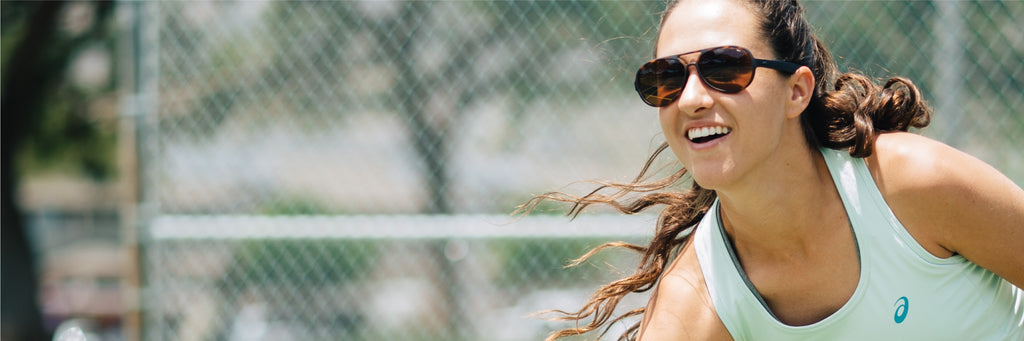 A woman playing tennis wears a pair of MagLock Osprey Sunglasses by Distil Union