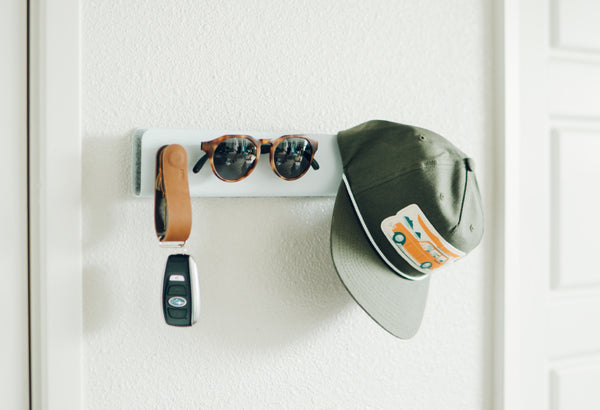 The Distil Union organizing solution ModStation hangs on a white wall with a KeyLoop, MagLock Sunglasses and Nick Kuchar hat