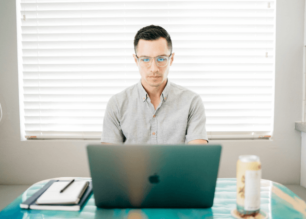 man in glasses sitting at laptop computer