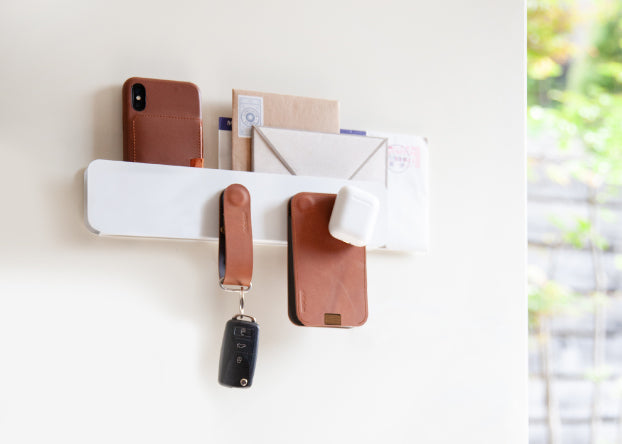 A white ModStation mounted a door with brown leather wallet and key organizer, part of the Ferris system