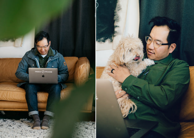 A man works on his laptop, accompanied by a dog