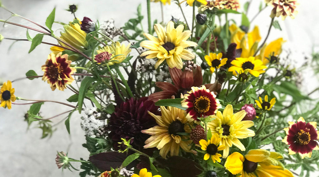 Autumn arrangement in warm colors with zinnias, sunflowers, and Black-eyed Susans.