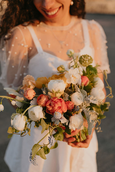 Beautiful spring wedding bouquet with warm colors and a touch of blue