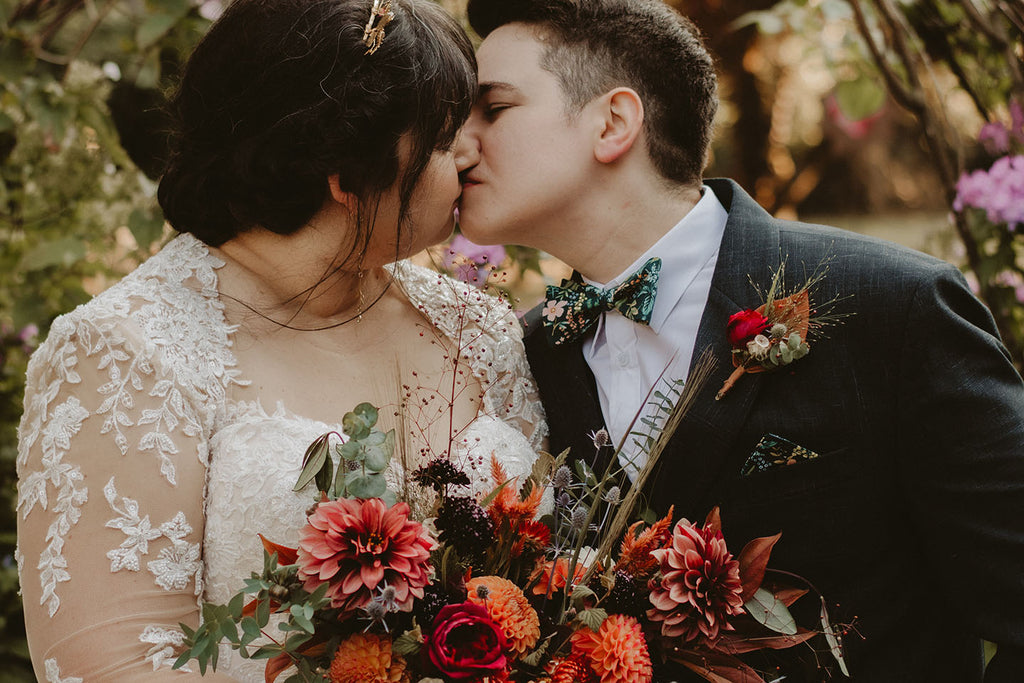 Couple kissing on their wedding day with unclose shot of floral details.