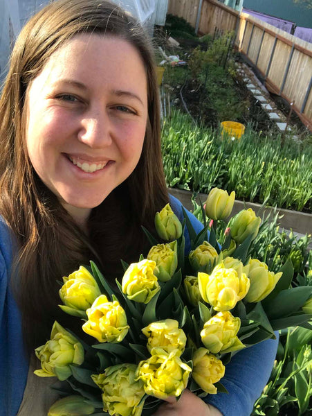 Laura holding a bunch of bright yellow double tulips.