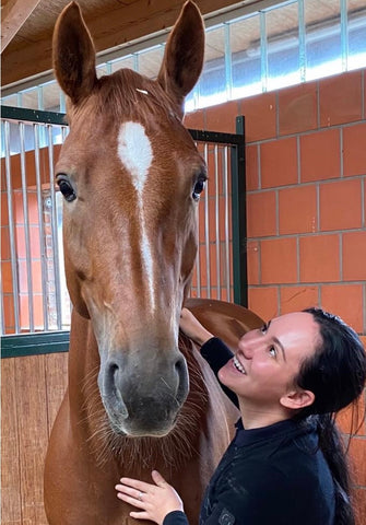 Hope next to a chestnut horse, named Tripple, smiling up at him. 