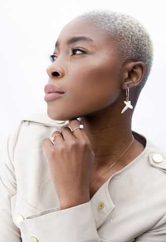 Side portrait of model wearing two pearl rings and pearl earrings