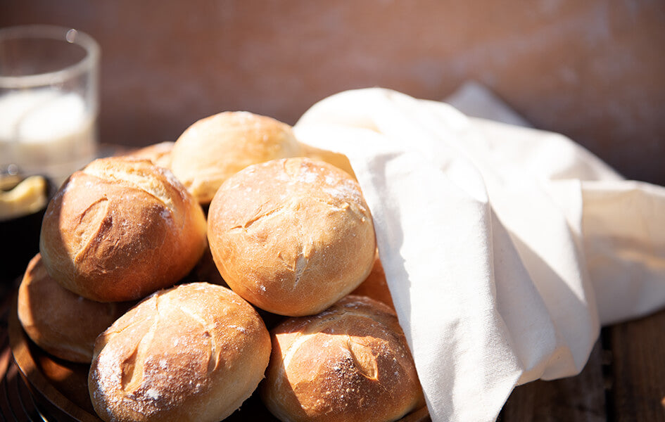 Fresh bread rolls falling out of a brilliant white cotton bread bag