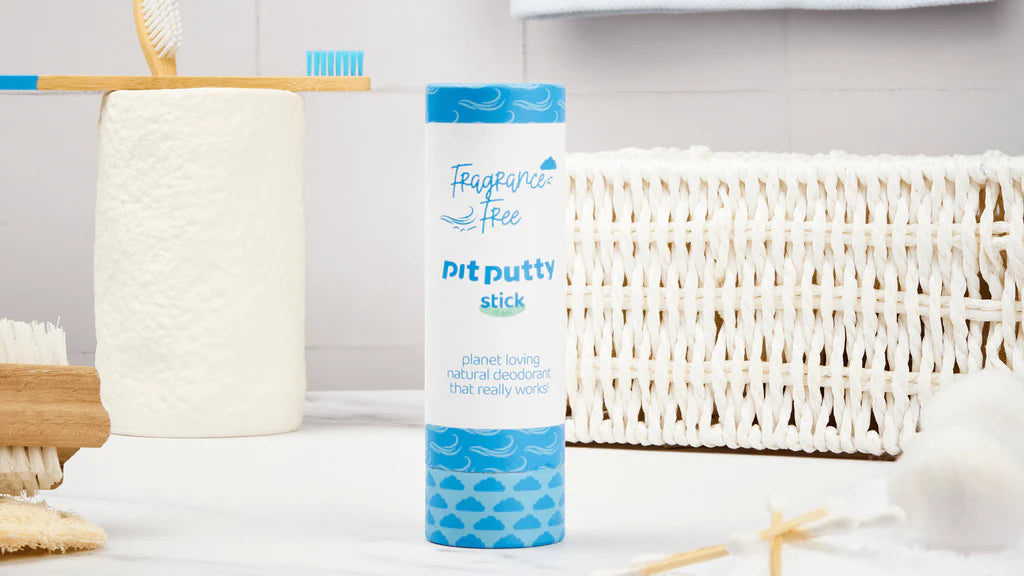 A Pit Putty blue natural deodorant stick in a bathroom setting next to toothbrushes and toilet roll