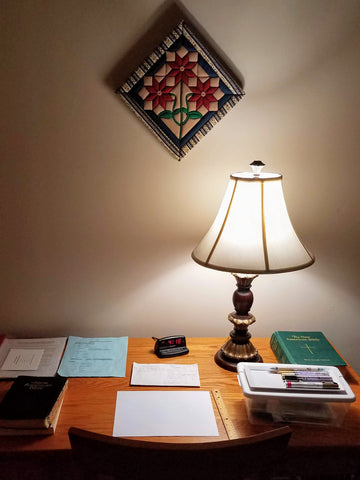 Desk with lamp, Bible, paper, and pens
