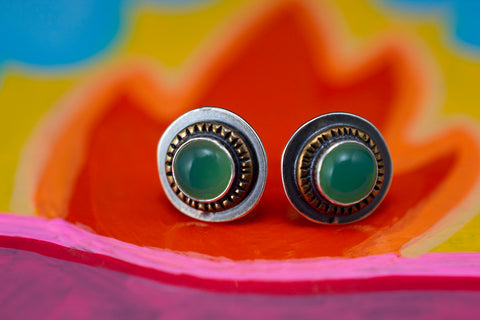 green stud earrings on painted background