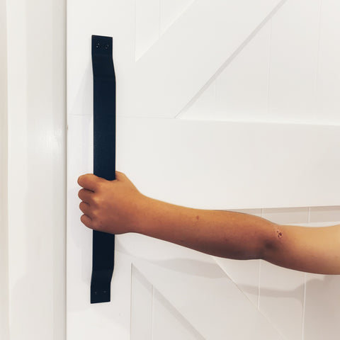 child opening white barn door with large black handle