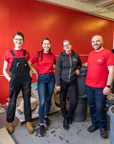 Team at Kuma Coffee smiling in Red Bear Kuma shirts and posing with coffee roasted for the day