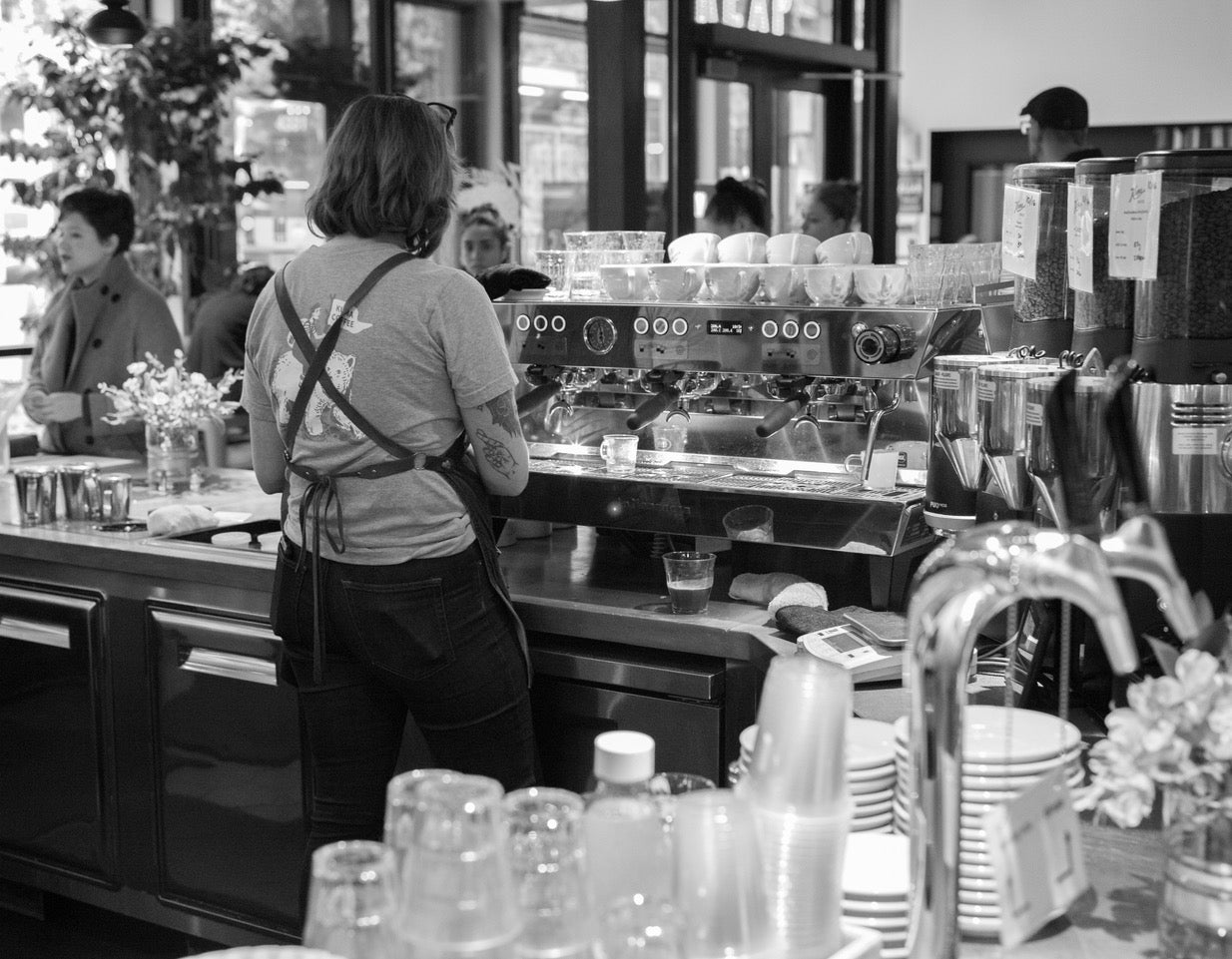 Kylie making espresso at La Marzocco Cafe in Seattle, WA wearing a summer adventures Kuma Coffee shirt