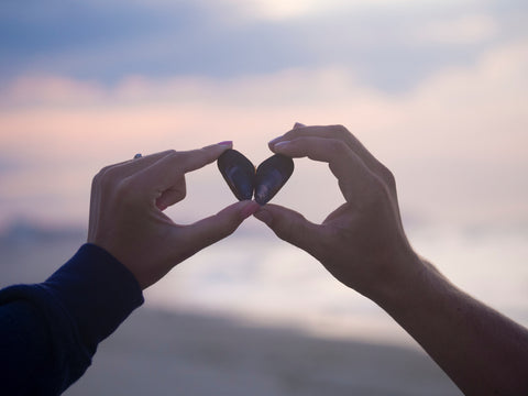Couple holding shells so it looks like a heart.