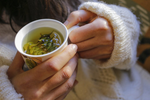 remèdes naturels thé dans les mains d'une femme