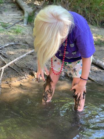 A muddy Pearl playing in the river at coral farms summer camp