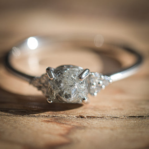 Rough diamond ring with a gray rough diamond and cut diamond cluster sidestones in 14k white gold