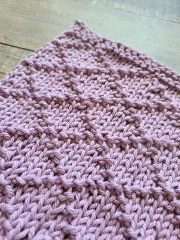 Facet dishcloth laying on a wood surface.