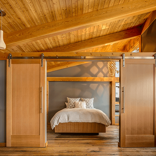 Double single panel barn doors with stainless steel hardware in a large bedroom space