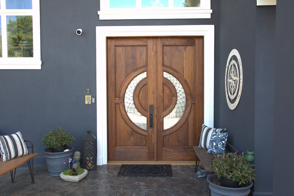 walnut front door with crescent shaped glass on blue house