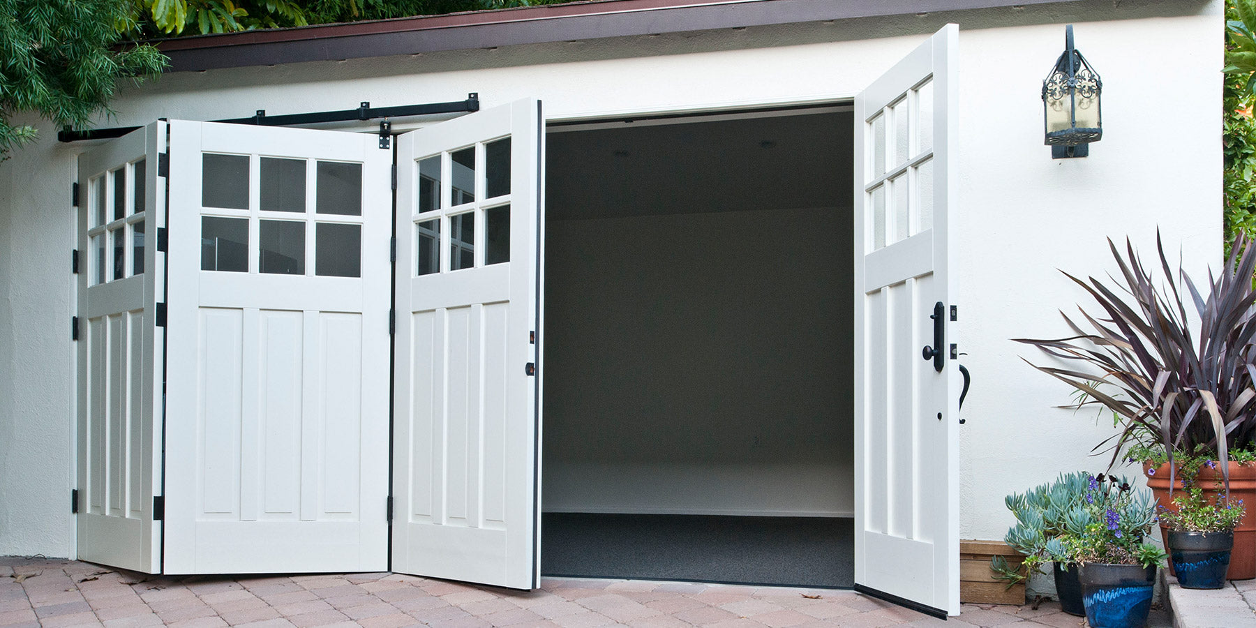 Set of white b-folding carriage doors half-opened in a garage set up. Photo by RealCraft.