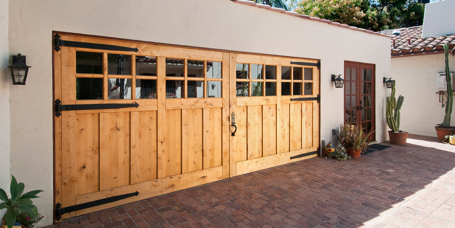 oversize Knotted carriage door with long strap hinges on a sunny day. Photo by RealCraft.