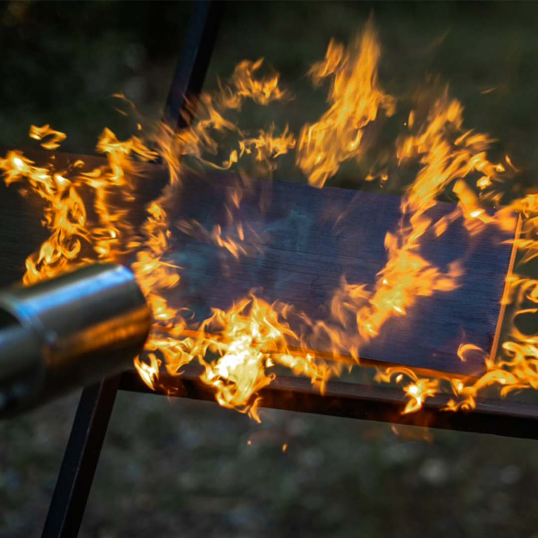wood plank on flames from a blow torch