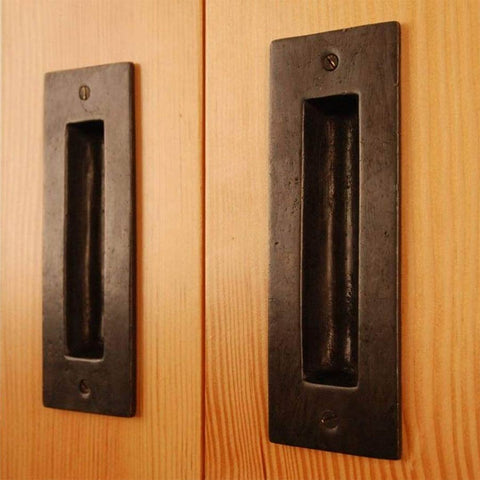two identical solid bronze flush pull handles in dark bronze finish on biparting doors