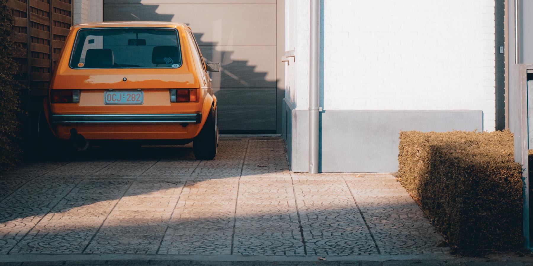 Clean home driveaway during sunset featuring a parked vintage yellow car.