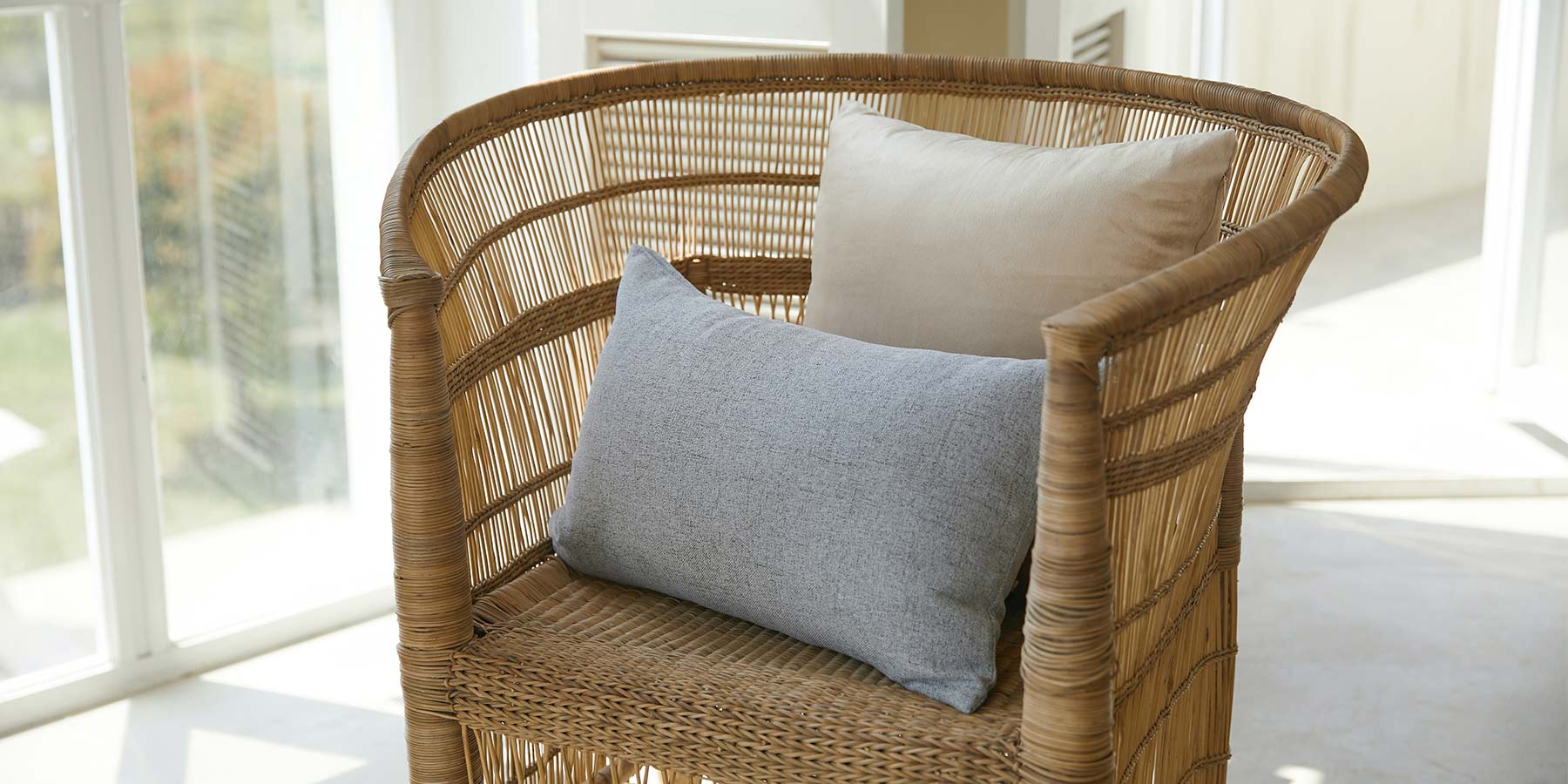 Rattan Chair with a white and a blue pillow on the seat area.