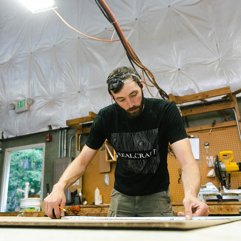 Craftsman measuring wood plank in a woodshop