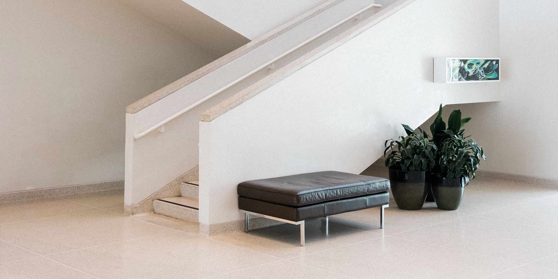 Interior concrete staircase with a leather stool and plants on the floor level