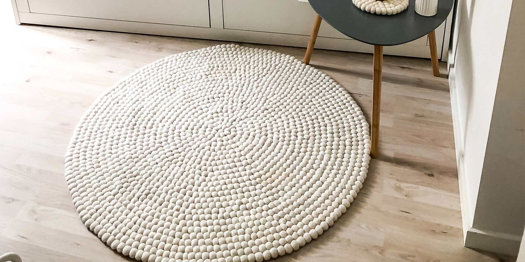 White woven circular area rug on a light wood floor.