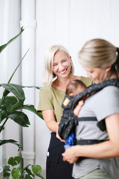 Eine Mutter versucht, ihr Kind zu stillen, während sie ein Babytrage von Tula benutzt.