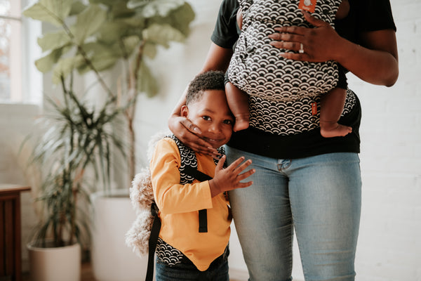 Un bambin et sa mère qui portent tous deux un porte-bébé Tula assorti.