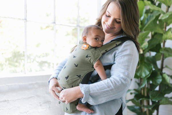 A mother smiling at her child that she is carrying in a baby carrier from Tula.