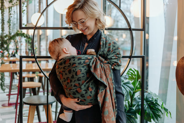 A mother looking at her child who is sitting in a Tula Ring Sling