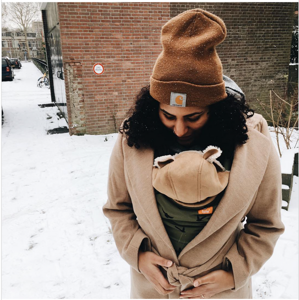 A mother carrying her child while being in the snow.