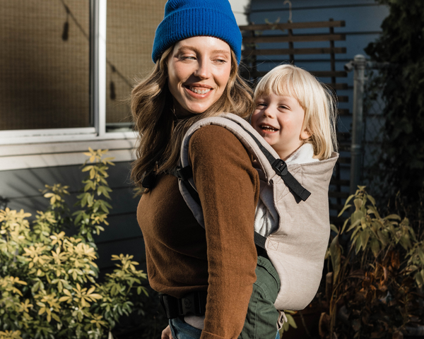 natalie and her son smile while she carries him in a toddler carrier