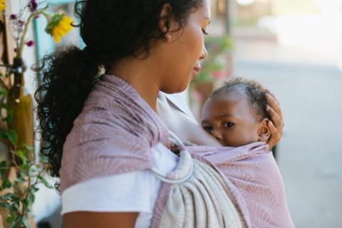 A mother breastfeeding her child in a Tula Ring Sling.