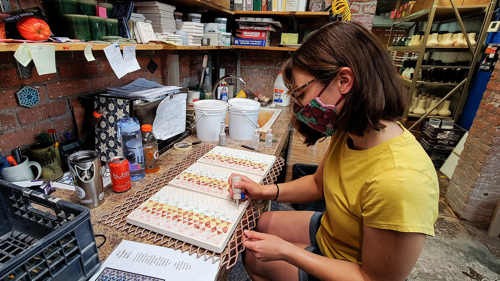 Photo of Glaze Technician, Lexie hand-painting a Pride Tile.