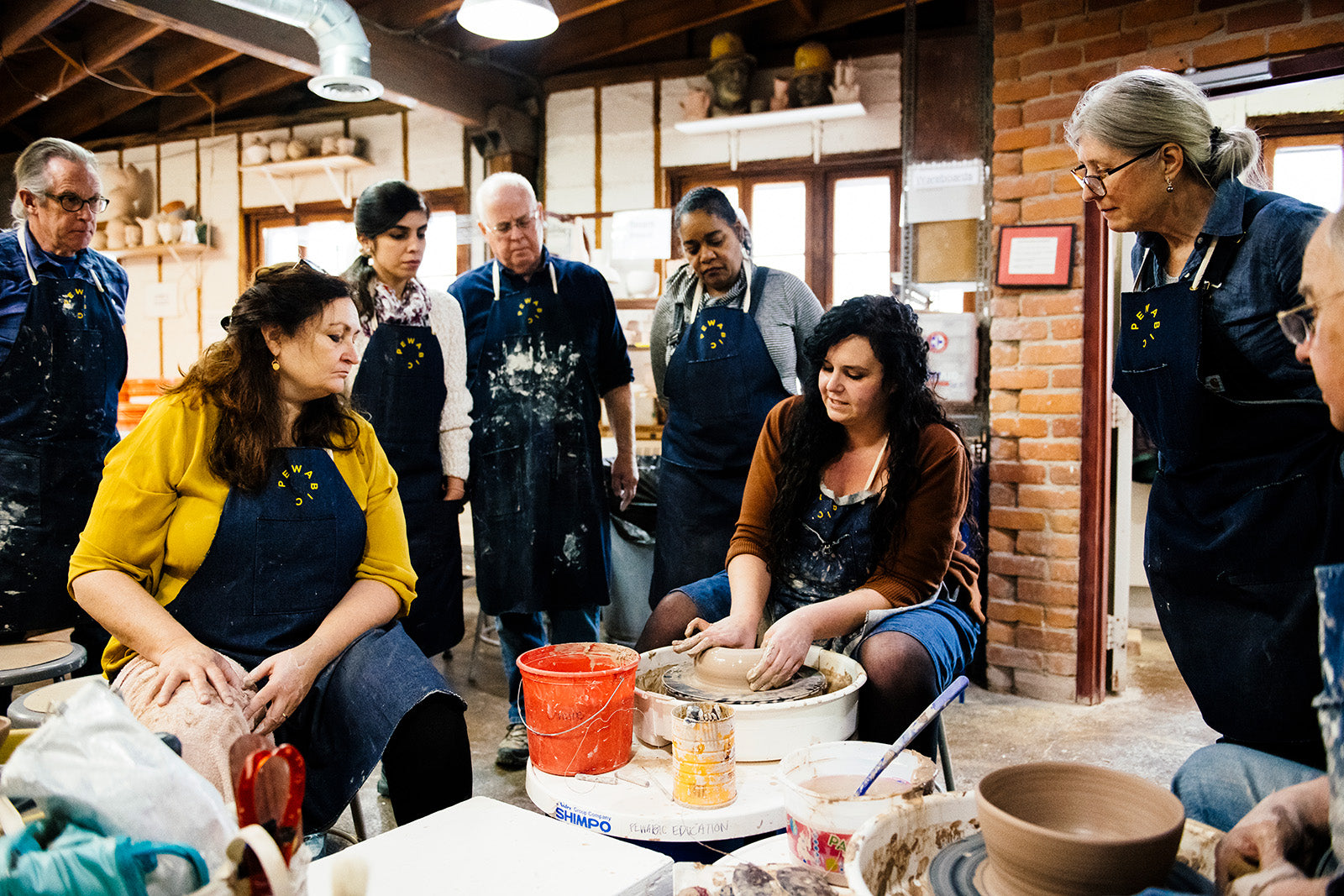 Education Director and Archivist Annie demonstrating wheel-throwing for her students.