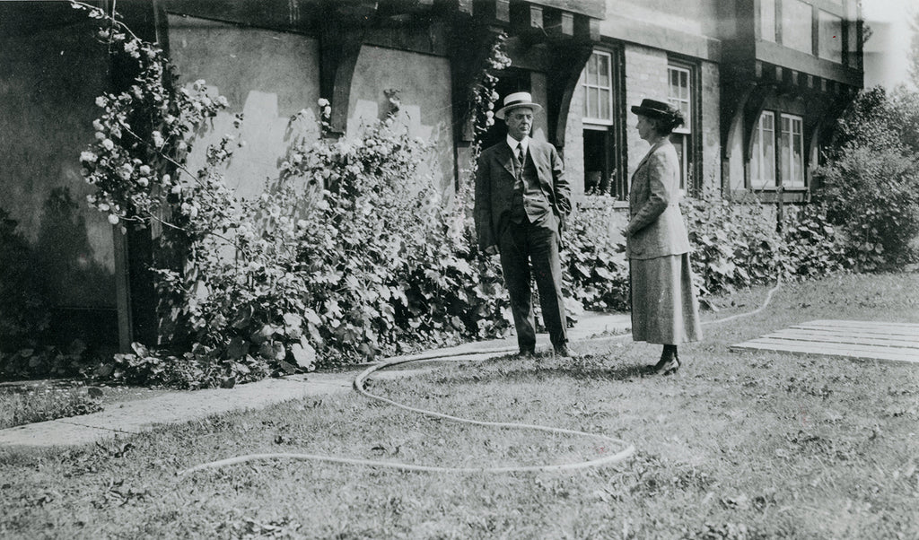 Pewabic Co-Founders Horace James Caulkins and Mary Chase Perry Stratton standing near Pewabic Pottery, circa 1918. You can see the ample hollyhocks on the exterior base of the National Historic Landmark building.