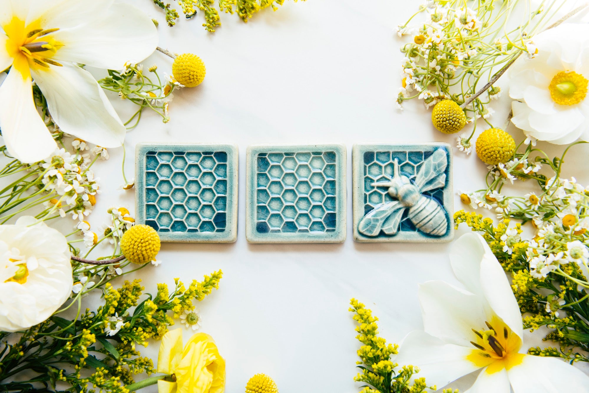 Blue glazed trio of tiles depicting a bee and two honey combs