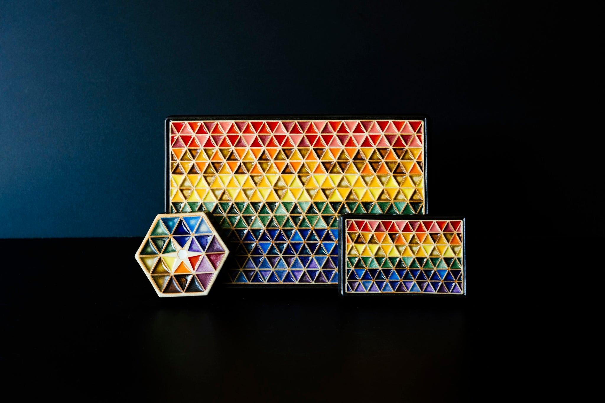 From left to right: Our Hex Paperweight, Large Pride, and Small Pride tiles all set against a midnight-blue backdrop. 