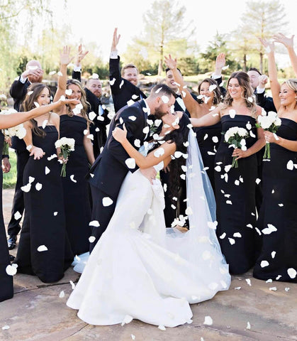 Bride and groom kissing surrounded by bridal party